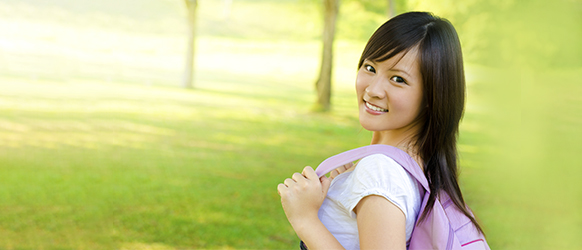 Young female student in standing outside in green space